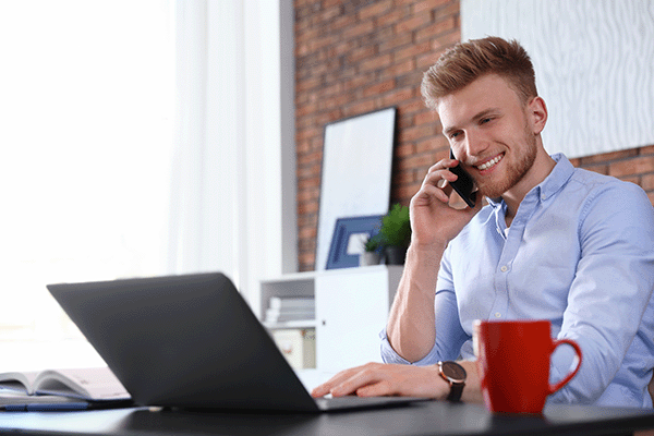 man on phone smiling at laptop